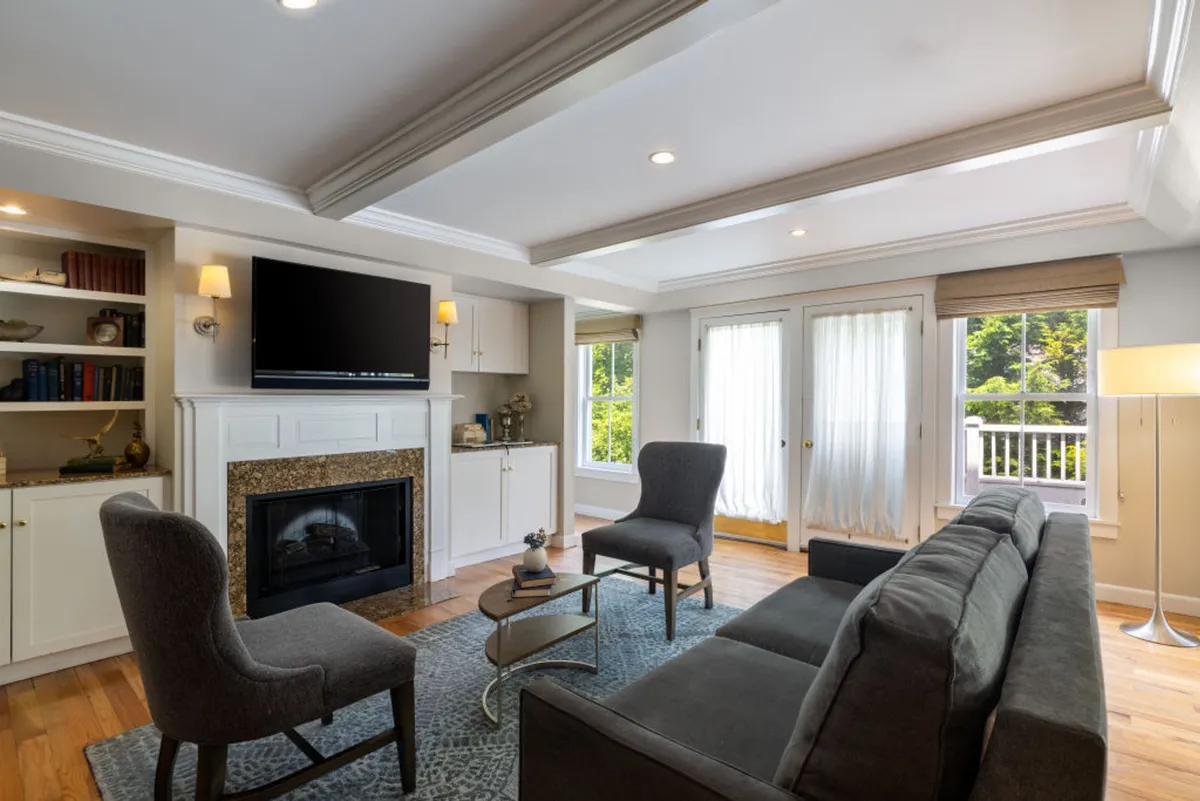 A spacious sitting area with a decorative fireplace, a plush sofa, a TV, and expansive windows letting in ample daylight. The setup is ideal for socializing, sipping morning coffee, and enjoying the warmth of the fire after outdoor adventures.